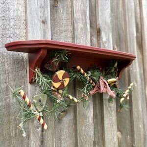 RED FARMHOUSE PEG WALL SHELF WITH HOLIDAY GREEN GARLAND & WOODEN CANDY